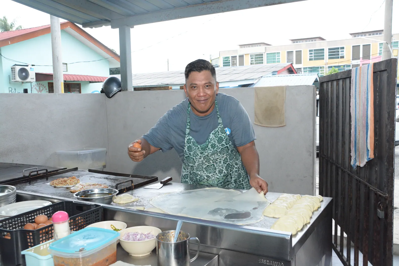 A cook preparing dough at an open-air kitchen counter