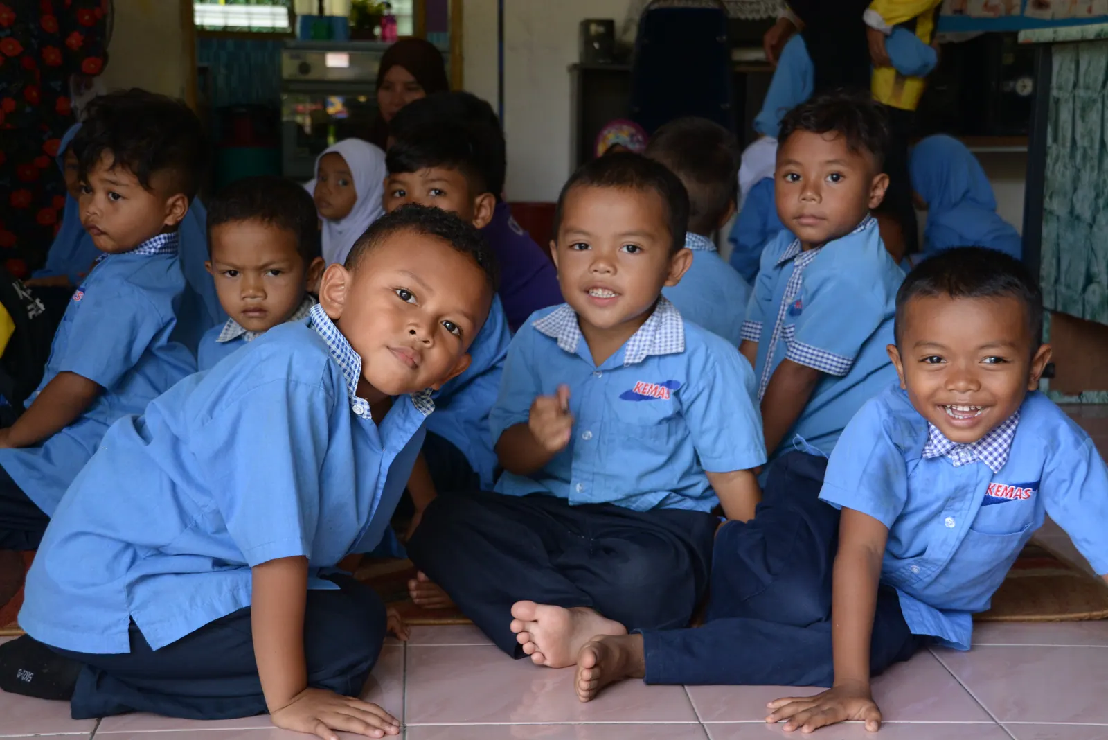 A lively group of preschool children in blue uniforms looking toward the camera